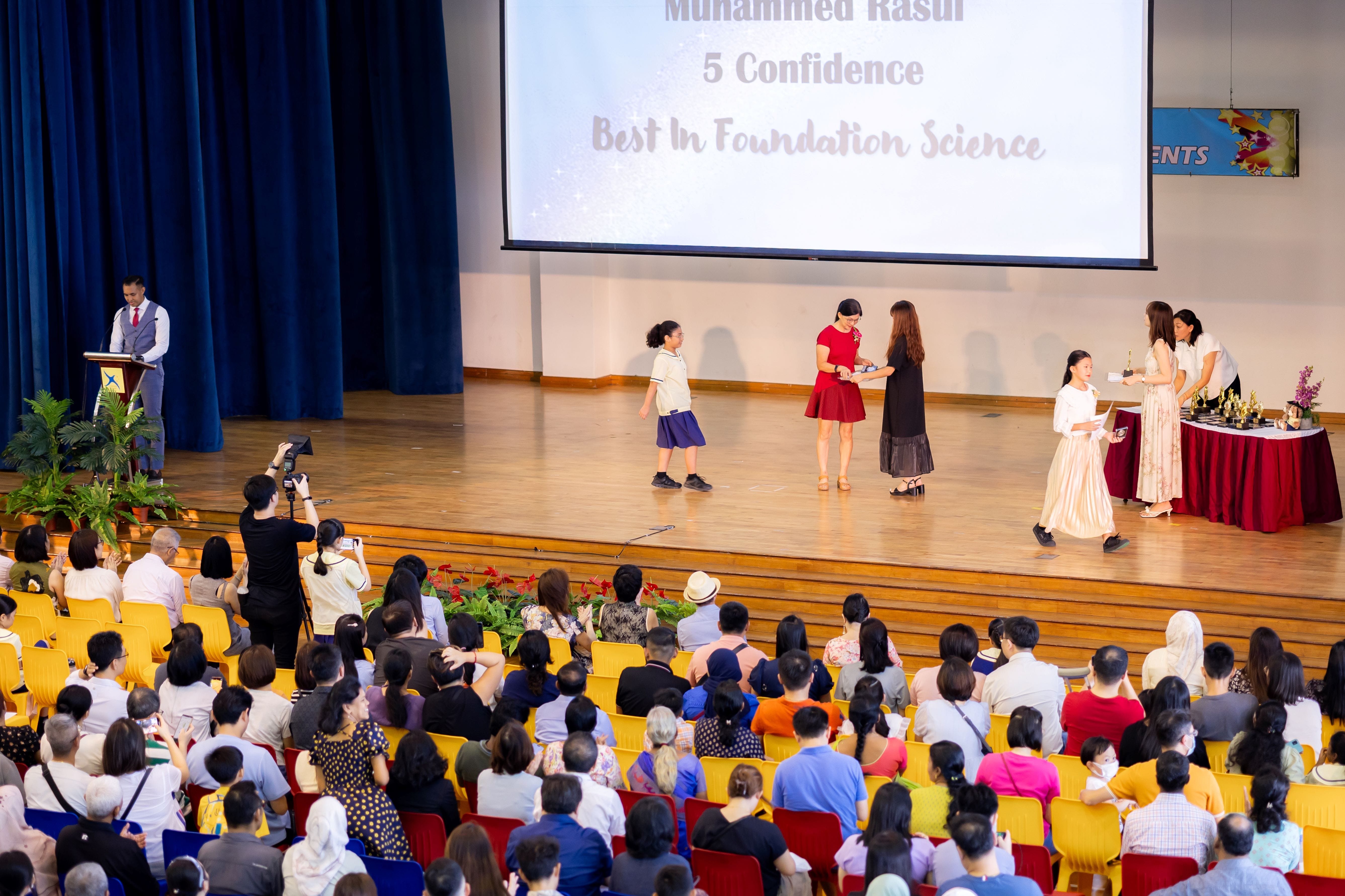 A student on the stage walking over to the prize presenters to receive her award